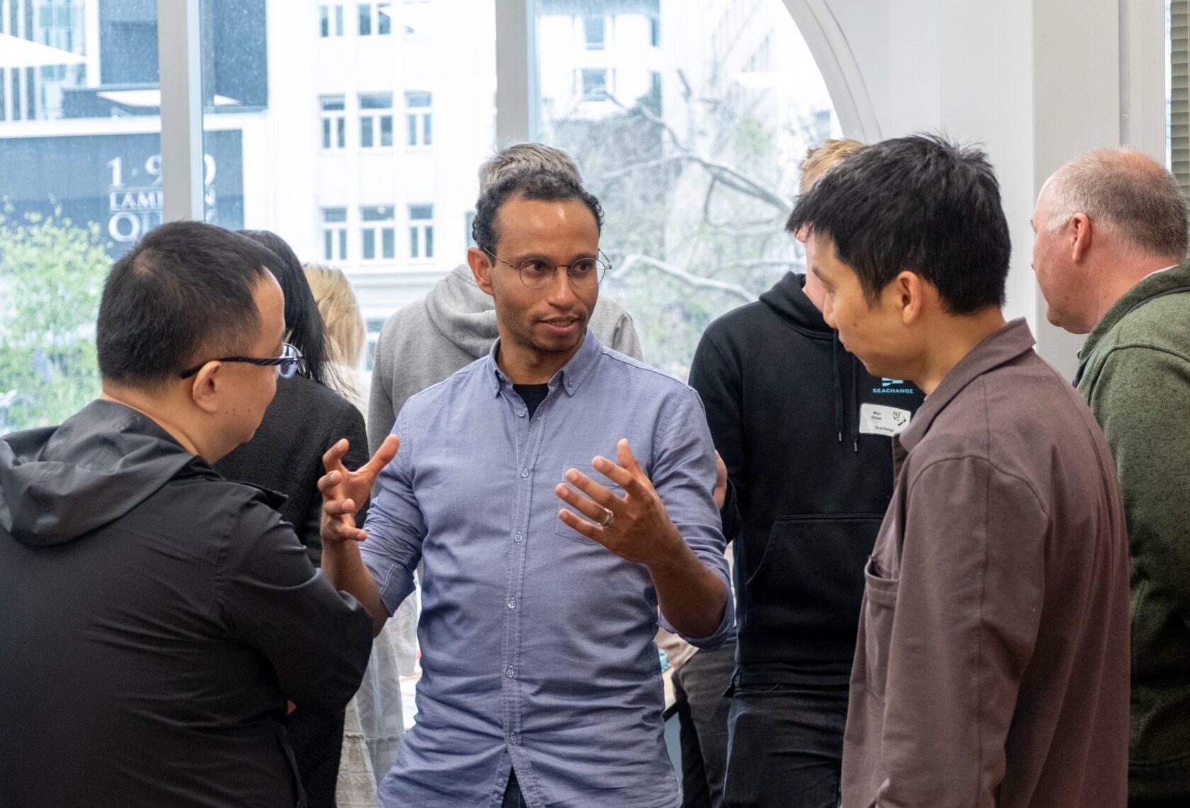 A group of attendees in conversation by the arched windows at FCB Wellington