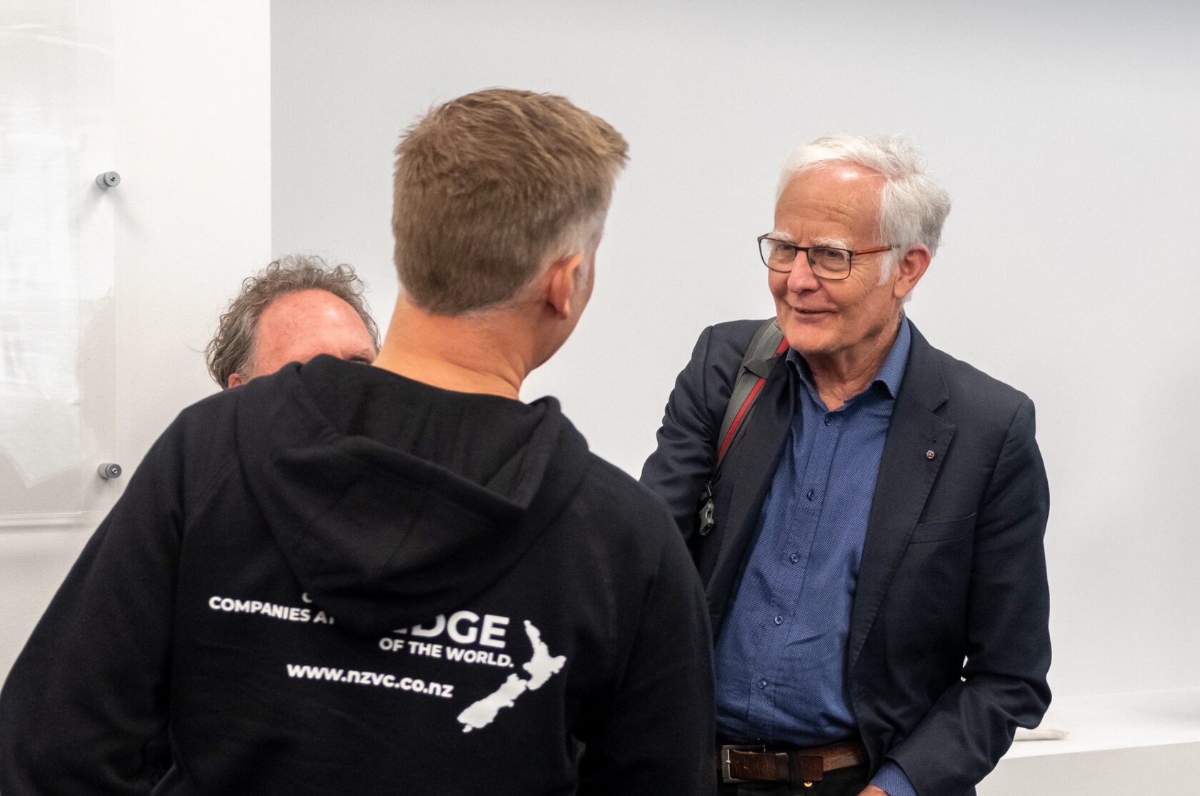 Two attendees talking, one in a jacket reading companies at the edge of the world