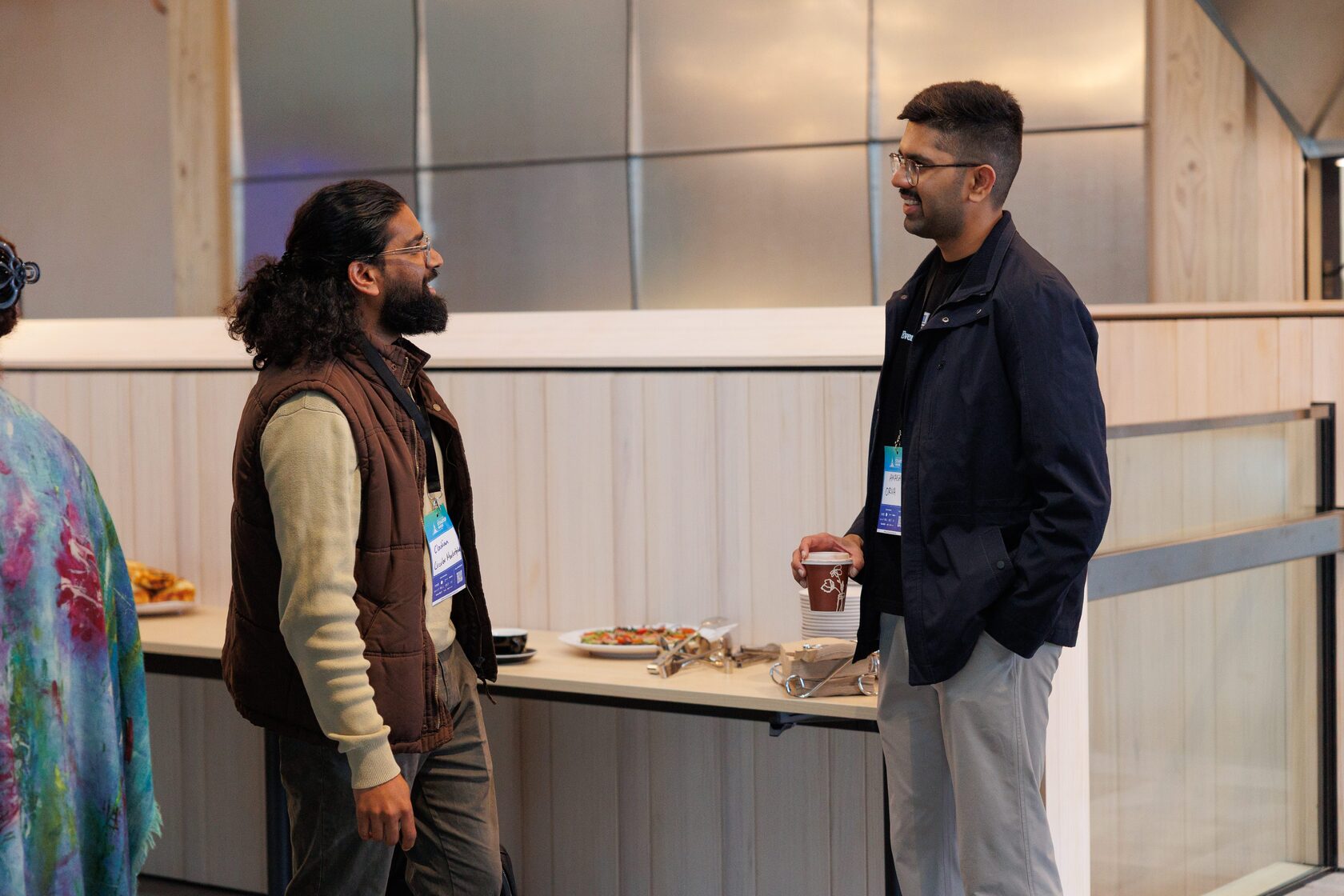 Two attendees talking over coffee beside the catering counter as Portfolio Day 2025 opens