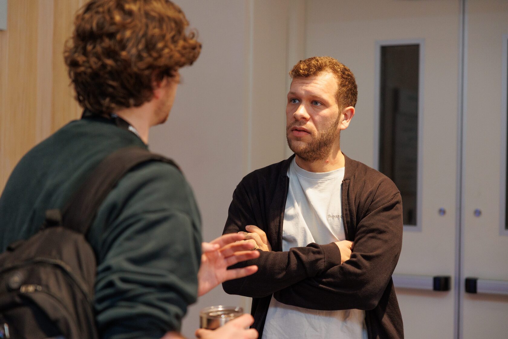 Two attendees talking against a wall away from the main room