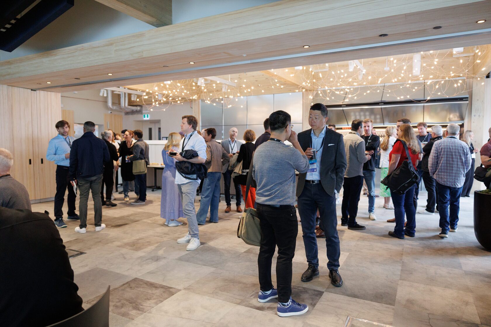 A wide view of the Pipiri Lane foyer filled with attendees under festoon lights