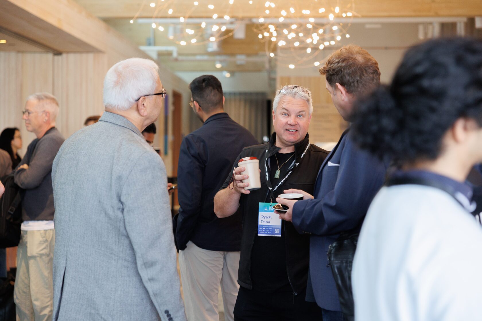 Attendees talking in a loose circle under the festoon lighting of the foyer