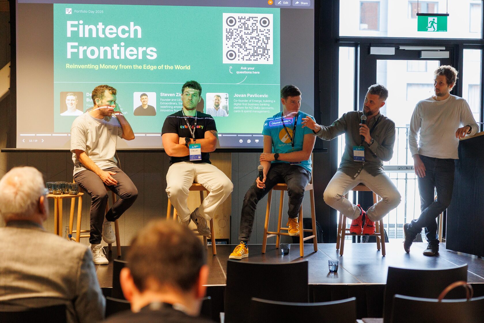 The Fintech Frontiers panel seated on stools in front of the session slide
