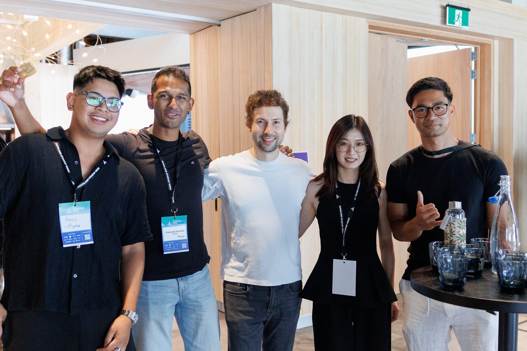 Five attendees posing together beside the drinks table at Portfolio Day 2025