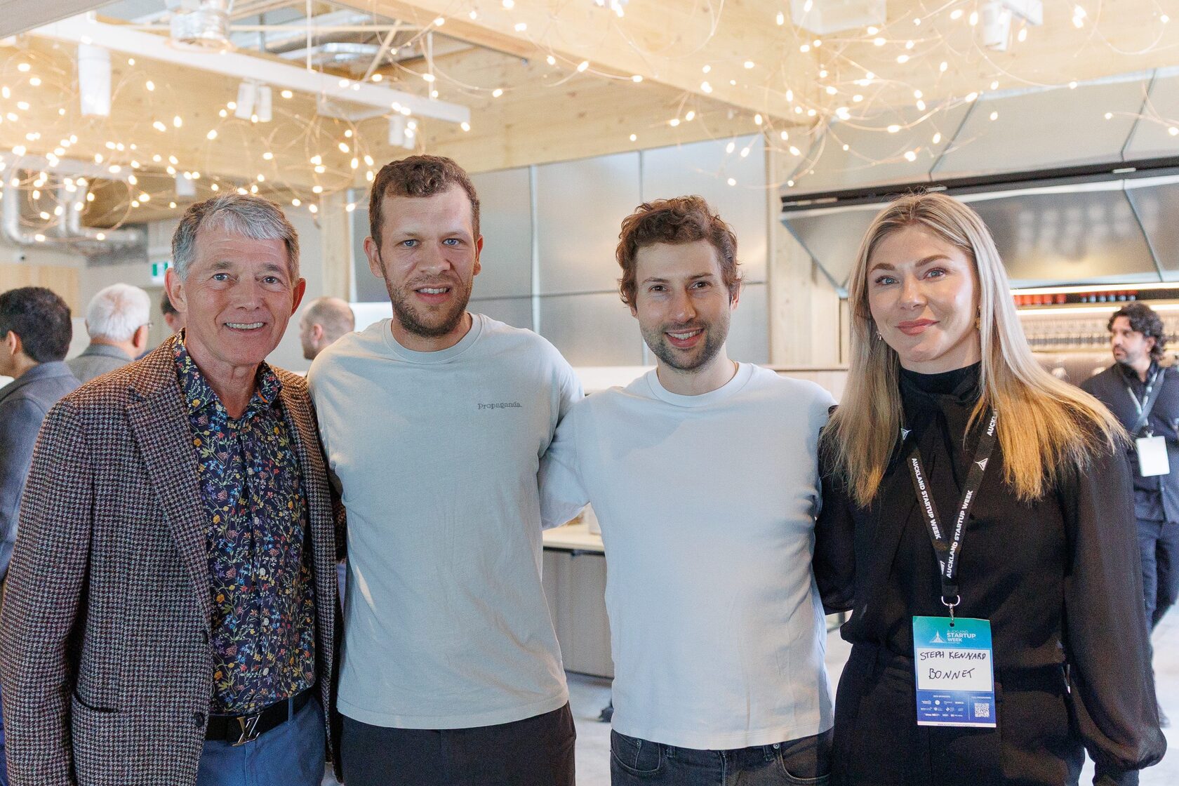 Four attendees standing together under festoon lighting at NZVC Portfolio Day 2025