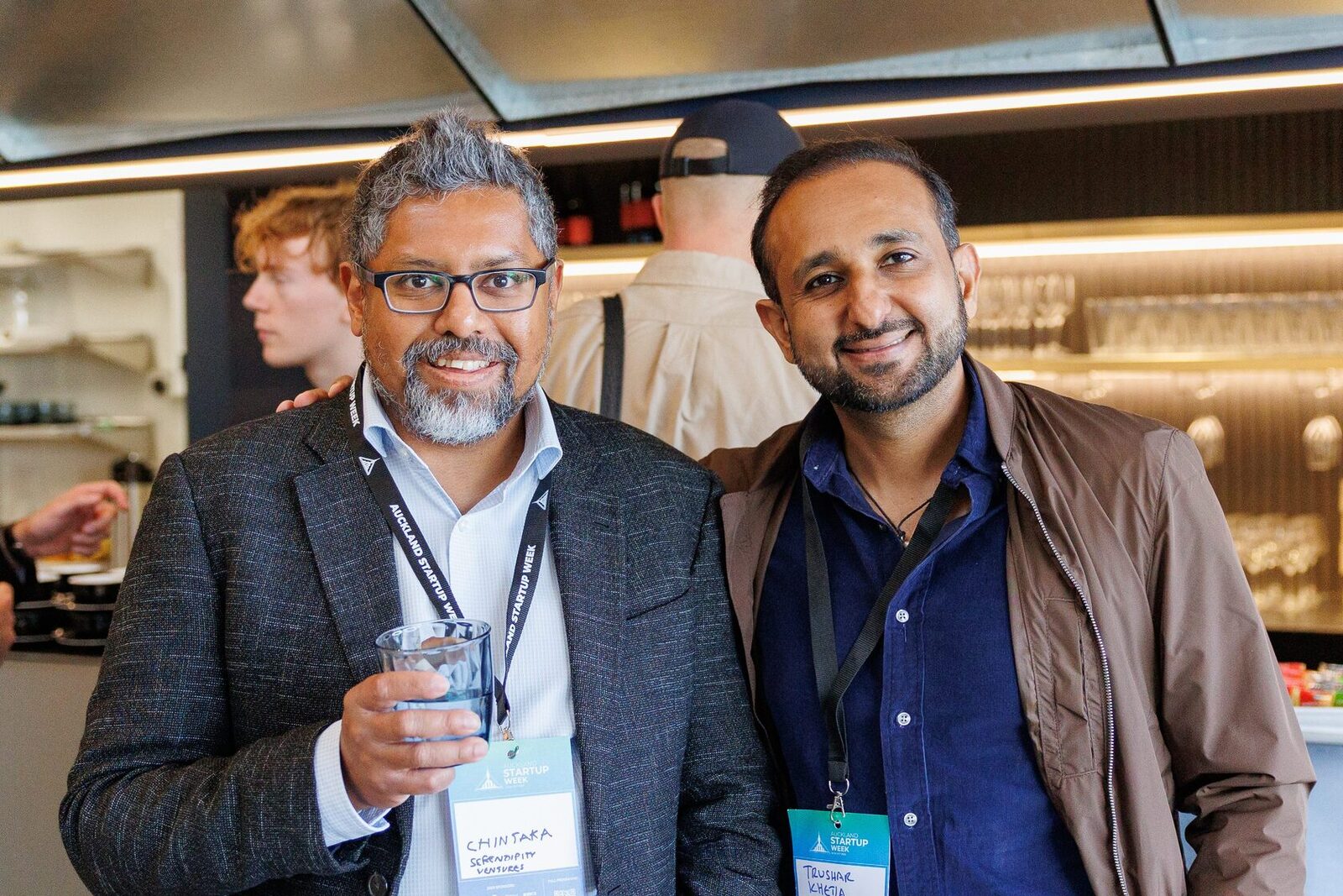 Two attendees holding drinks and talking to the camera at the close of the day