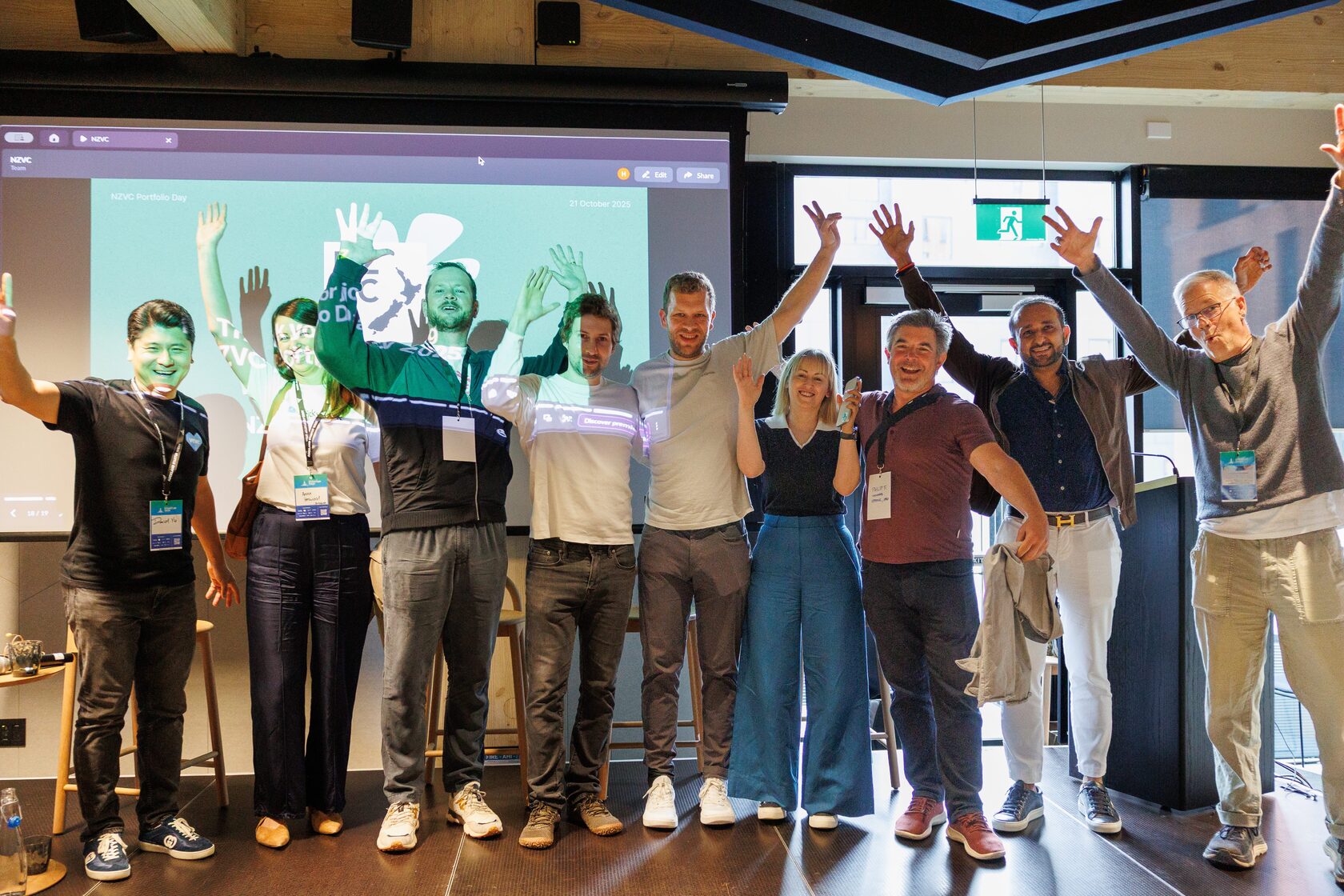 The whole room on stage with their arms raised as Portfolio Day 2025 closes