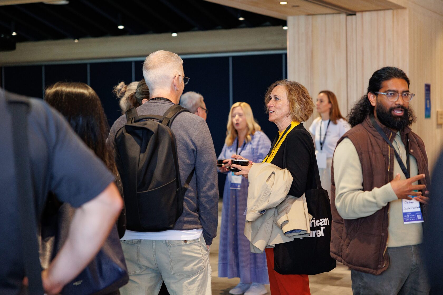 Attendees with backpacks and tote bags talking between sessions