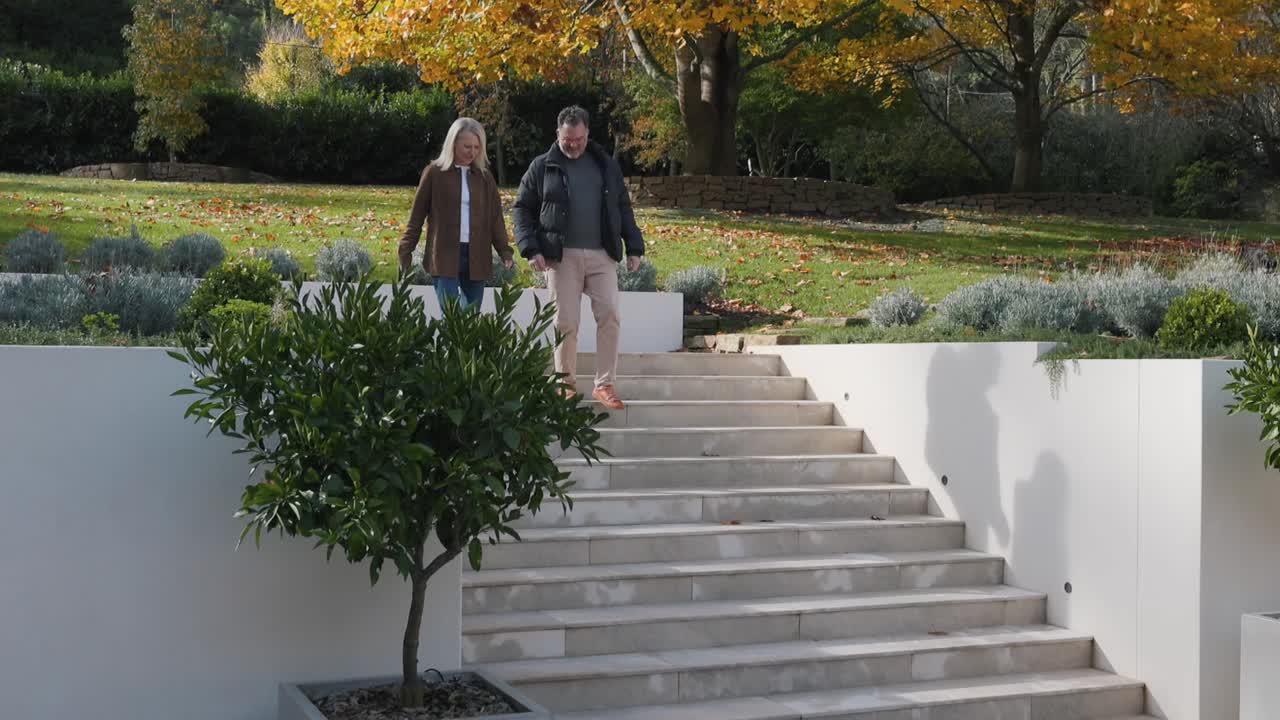 Two people climbing the front steps of a landscaped house