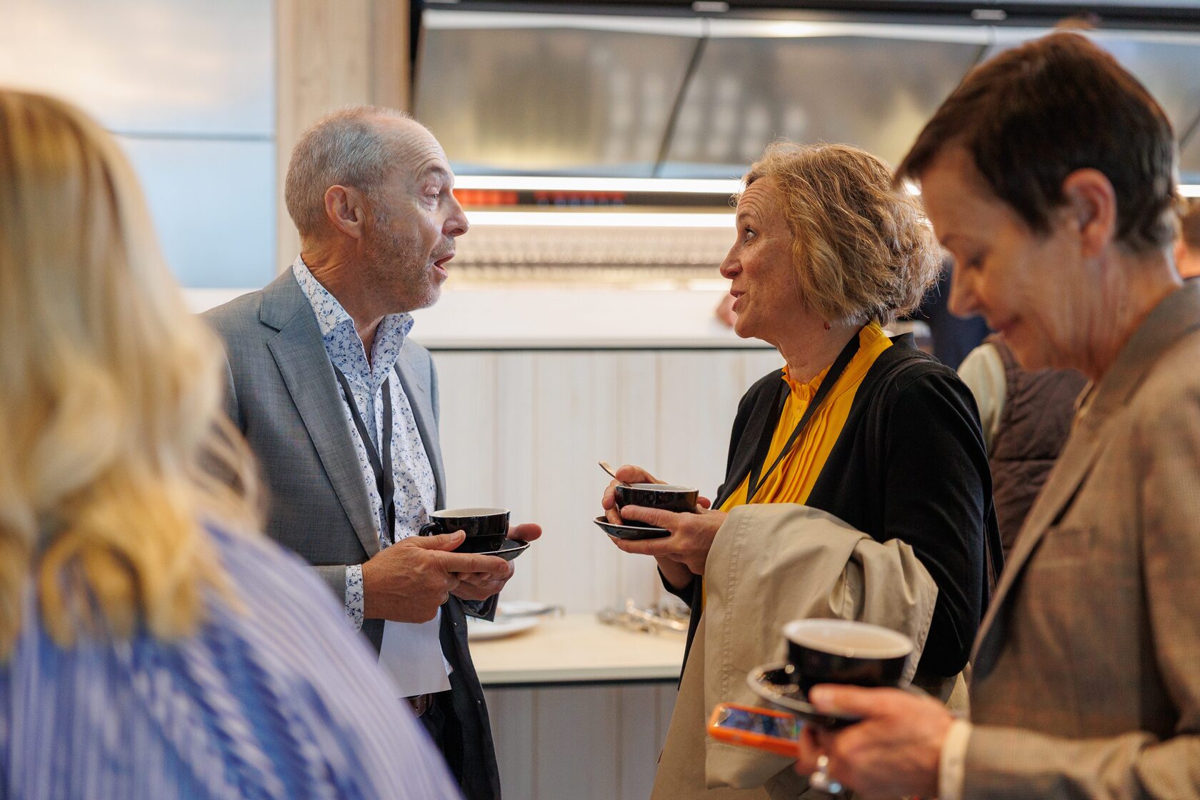 Three attendees talking over coffee cups at NZVC Portfolio Day 2025