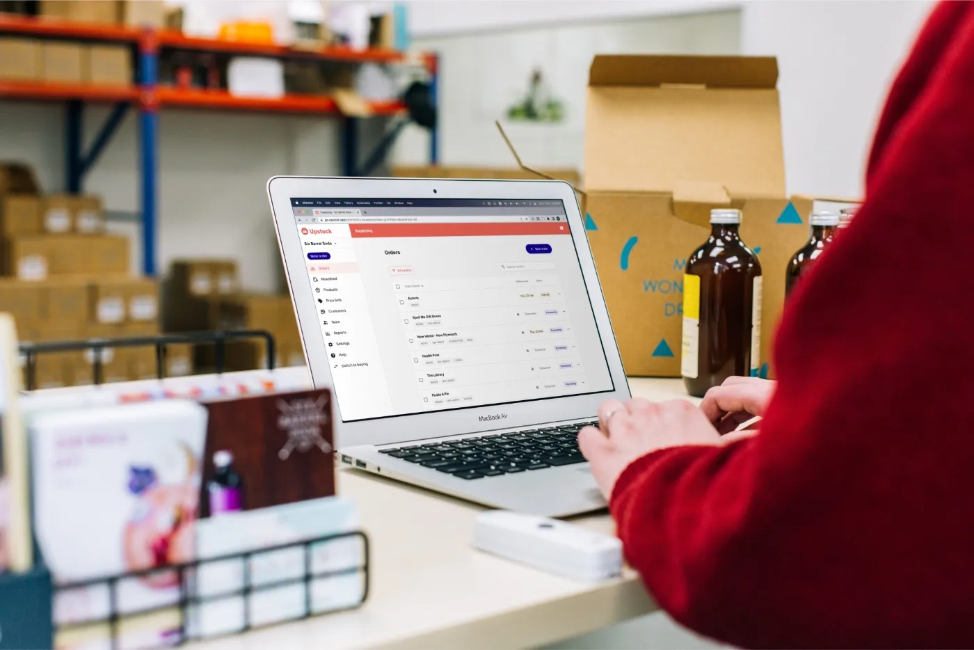 A supplier working through Upstock orders on a laptop in a warehouse